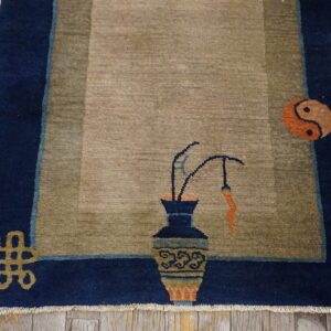 Khaki rug with a navy border featuring a vase, Yin-Yang symbol, and an endless knot on distressed wood.