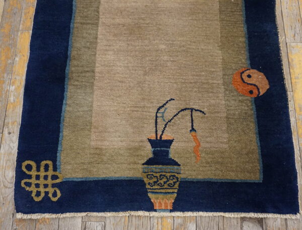 Khaki rug with a navy border featuring a vase, yin-yang symbol, and an endless knot on distressed wood.