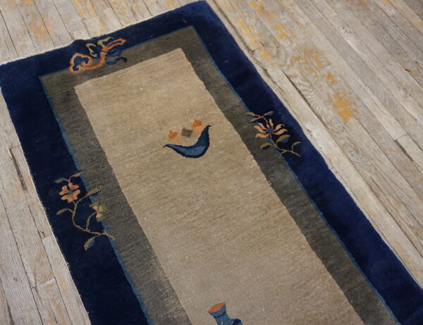 Beige runner with wide navy borders and sparse orange and blue decorative motifs on weathered wood floors.