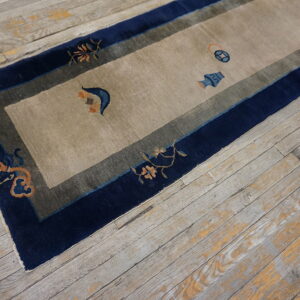 Runner rug featuring a tan field, navy border, and small orange and blue decorative motifs on wood flooring.