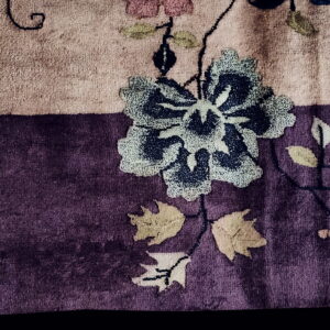Plush rug detail showing a dark blue floral pattern and leaves across dusty pink and deep purple fields.
