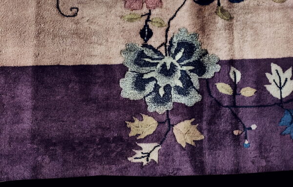 Plush rug detail showing a dark blue floral pattern and leaves across dusty pink and deep purple fields.