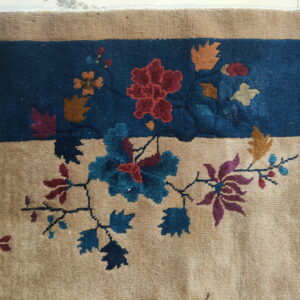 Beige rug border and deep blue field separated by stylized red, blue, and gold floral patterns.