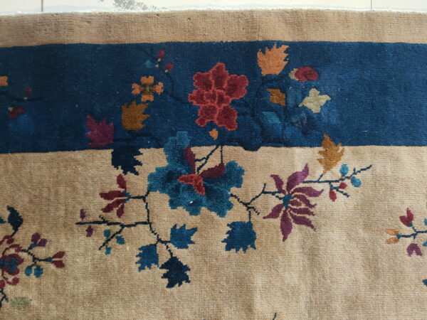 Beige rug border and deep blue field separated by stylized red, blue, and gold floral patterns.