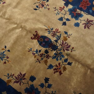 Beige field rug with a multicolored floral pattern, central blue vase motif, and deep blue corner accents.