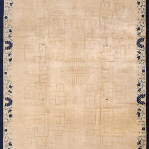 Tan rug featuring a low-contrast geometric pattern, framed by a dark blue border with vine and floral motifs.