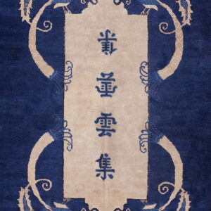 Blue rug with a rectangular beige cartouche containing characters, surrounded by stylized tan animal and vine motifs.