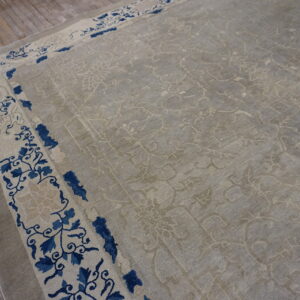 Light gray patterned rug with a cream and navy blue floral border visible on rustic wood flooring.