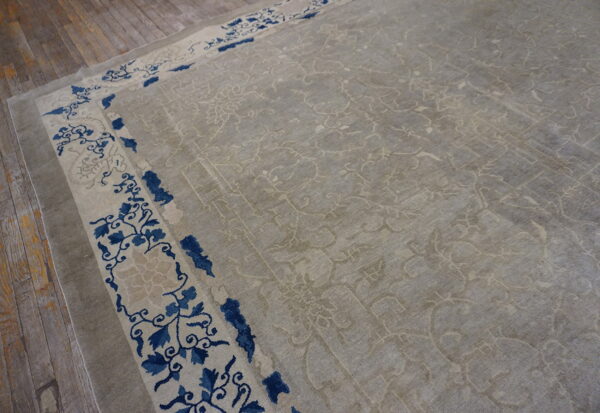 Light gray patterned rug with a cream and navy blue floral border visible on rustic wood flooring.
