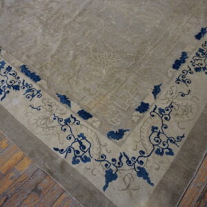 Beige low-pile rug with a blue floral border resting on distressed wood plank flooring.