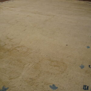 A low-angle view of a distressed tan rug bordered by indigo lines and symbols near dark wood flooring.