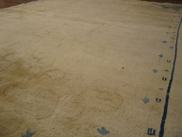 A low-angle view of a distressed tan rug bordered by indigo lines and symbols near dark wood flooring.