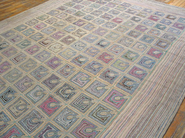 A heavily textured low-pile rug features colorful squares and looping motifs on a light beige background over wood floor.