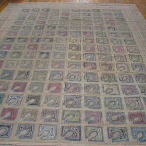 Textured beige rug with an all-over grid of abstract squares in varied colors rests on wood flooring.