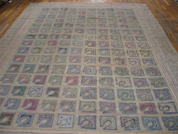 Textured beige rug with an all-over grid of abstract squares in varied colors rests on wood flooring.