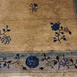 Tan rug field with scattered dark blue flowers framed by a decorative blue and gray botanical border.