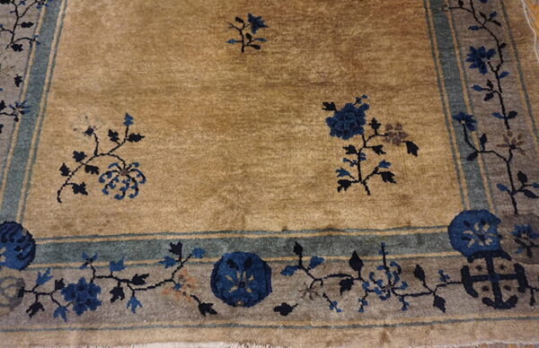 Tan rug field with scattered dark blue flowers framed by a decorative blue and gray botanical border.