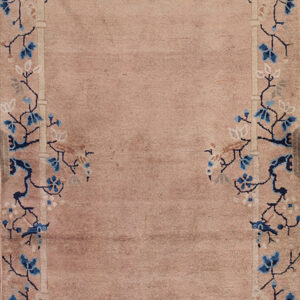 A beige runner rug with a navy and light blue floral border lies on worn yellow hardwood floors.