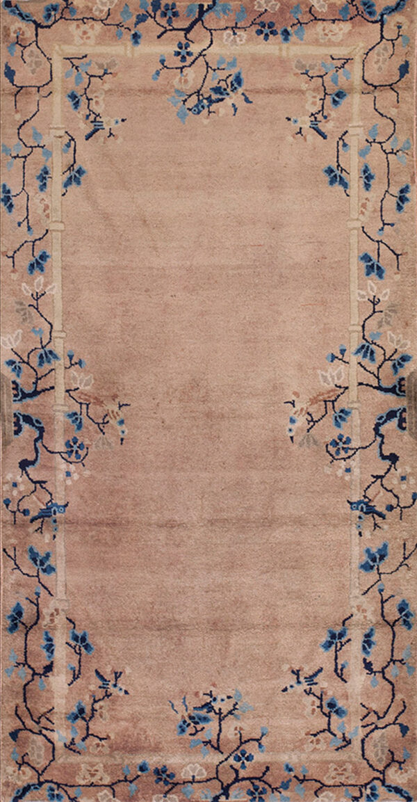 A beige runner rug with a navy and light blue floral border lies on worn yellow hardwood floors.