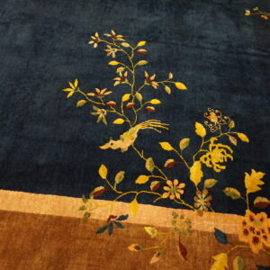 Plush dark blue rug with a yellow floral and bird motif bordering a wide brown band.