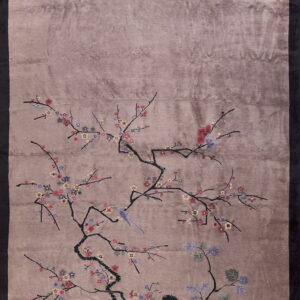 A glossy taupe rug featuring a detailed branch pattern with small multicolored flowers and a blue bird.
