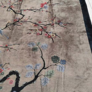 Taupe, low-pile rug with a stylized floral and bird pattern, bordered in dark blue.