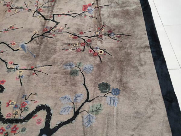 Taupe, low-pile rug with a stylized floral and bird pattern, bordered in dark blue.