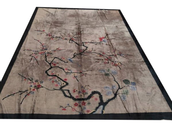 Mottled taupe rug with a dark border features an ornate black branch, pink flowers, and a light blue bird.