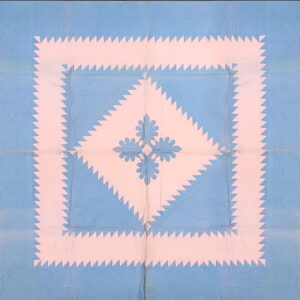 A blue and pink flat rug displaying a geometric sawtooth border around a stylized central floral pattern.