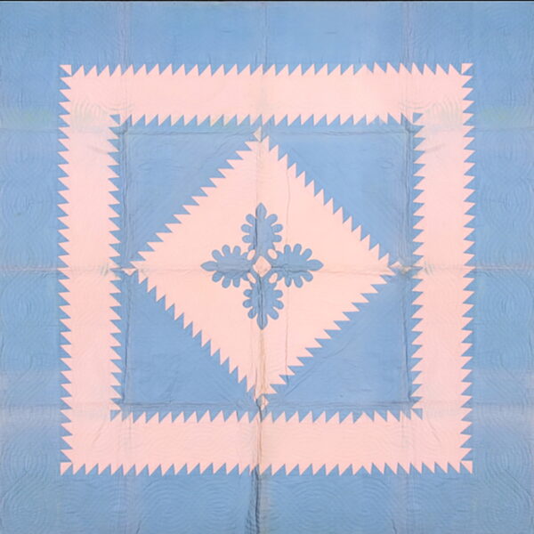 A blue and pink flat rug displaying a geometric sawtooth border around a stylized central floral pattern.