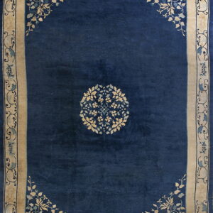 Navy blue rug featuring a circular floral motif and wide beige borders with stylized blue vines.