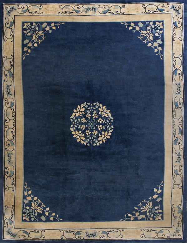 Navy blue rug featuring a circular floral motif and wide beige borders with stylized blue vines.
