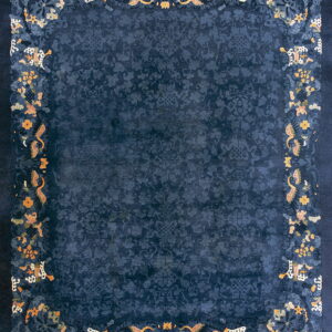 Deep blue rug with an ornate orange and yellow floral border surrounding a tone-on-tone patterned field.