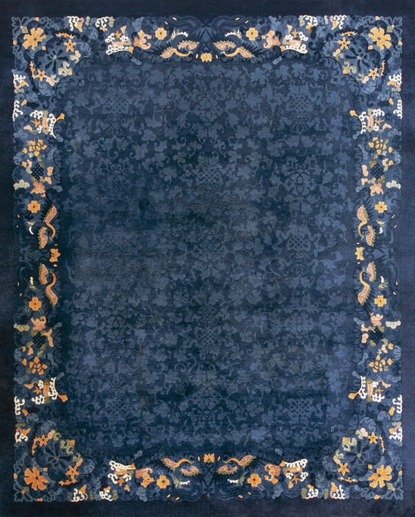 Deep blue rug with an ornate orange and yellow floral border surrounding a tone-on-tone patterned field.
