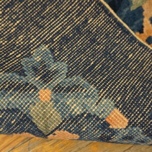 Detailed view of a navy rug's woven reverse side, showing the foundation structure and colorful tan, blue, and green knots.