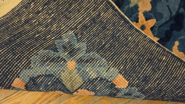 Detailed view of a navy rug's woven reverse side, showing the foundation structure and colorful tan, blue, and green knots.