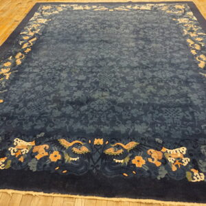 Navy blue rug with a subtle field pattern and a wide border of apricot and cream motifs on a wood floor.