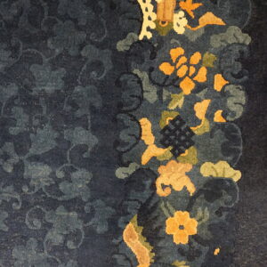 Deep blue floral rug featuring bright orange and green motifs bordered against light wood planks.