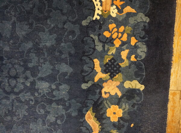 Deep blue floral rug featuring bright orange and green motifs bordered against light wood planks.