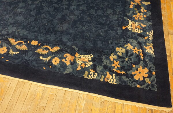 Plush navy blue rug featuring a dense tone-on-tone field and gold floral border on wood floors.