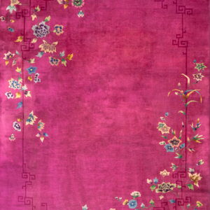 Fuchsia low-pile rug with geometric key border surrounding colorful cascading floral elements.