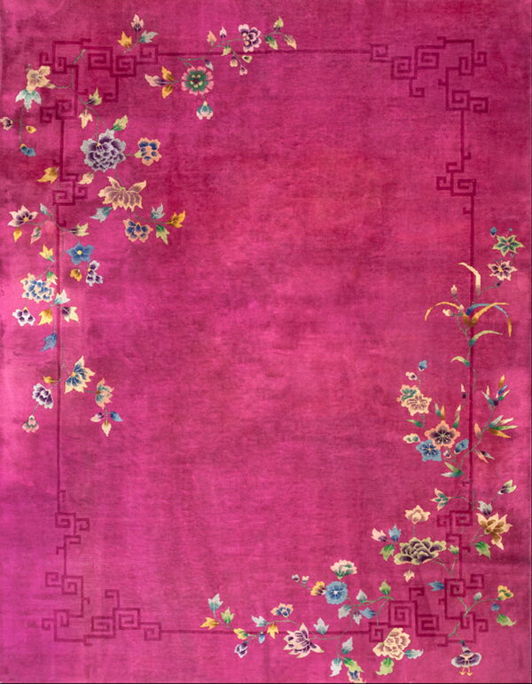 Fuchsia low-pile rug with geometric key border surrounding colorful cascading floral elements.