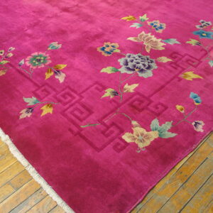 A magenta rug featuring pastel floral vines and a geometric border rests on golden hardwood floors.