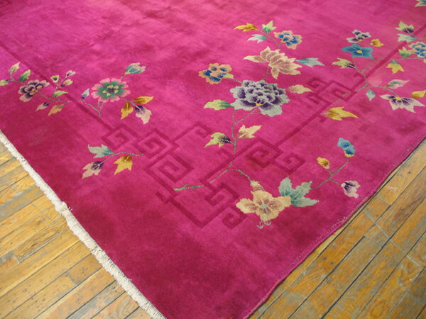 A magenta rug featuring pastel floral vines and a geometric border rests on golden hardwood floors.