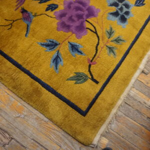 Mustard high-pile rug featuring purple and blue floral designs and a bird on distressed wood flooring.
