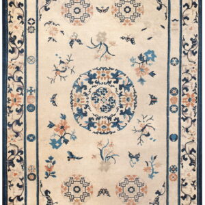 Cream rug with scattered blue and peach floral designs, a central medallion, and a thick blue border.