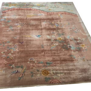 Distressed rug featuring a faded pink and brown scenic pattern of birds, flowers, and a central bridge.