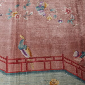 Mauve rug with a scenic pattern featuring colorful birds, florals, and a red railing over green water.