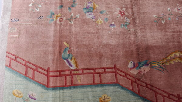 Red knotted antique 1920s room size wool rectangle chinese - art deco rug 7 Mauve rug with a scenic pattern featuring colorful birds, florals, and a red railing over green water.