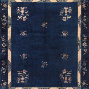 Dark blue rug featuring floral vases and scatter motifs, framed by a thick tan border with geometric details.
